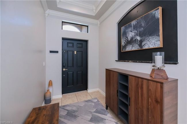 Entryway with crown molding, light tile patterned flooring, baseboards, and a raised ceiling | Image 14