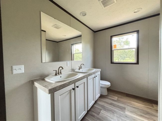 Full bath featuring double vanity, wood look finished floors, crown molding, and a textured ceiling | Image 9