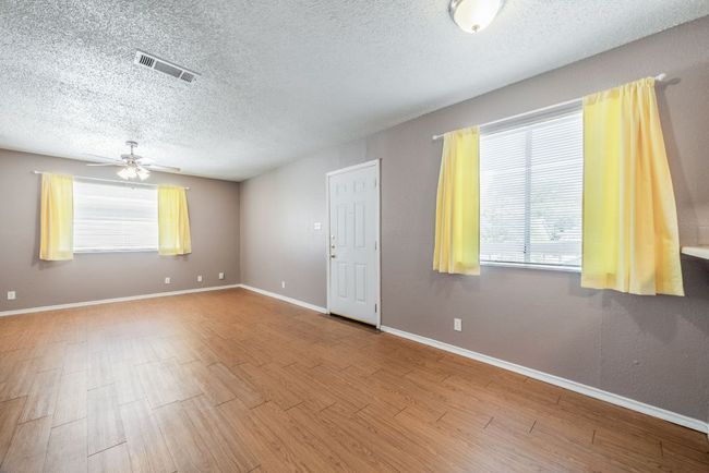 Empty room featuring a textured ceiling, ceiling fan, and wood finished floors | Image 13