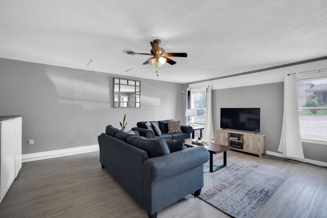 Living room featuring wood finished floors, plenty of natural light, baseboards, and ceiling fan | Image 13