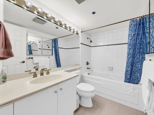 Bathroom with shower / tub combo, visible vents, toilet, tile patterned flooring, and vanity | Image 12