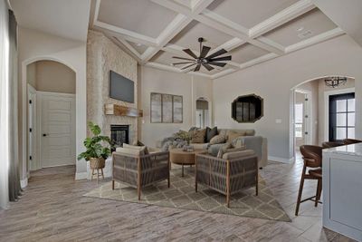 Living room featuring coffered ceiling, a stone fireplace, beam ceiling, ceiling fan, and a towering ceiling | Image 2