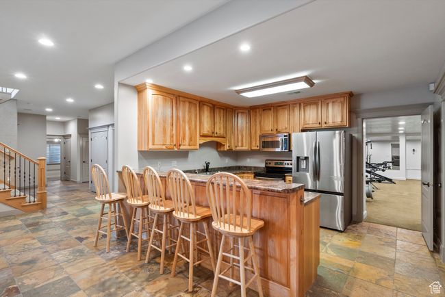 Kitchen with appliances with stainless steel finishes, a kitchen bar, recessed lighting, a peninsula, and a sink | Image 60
