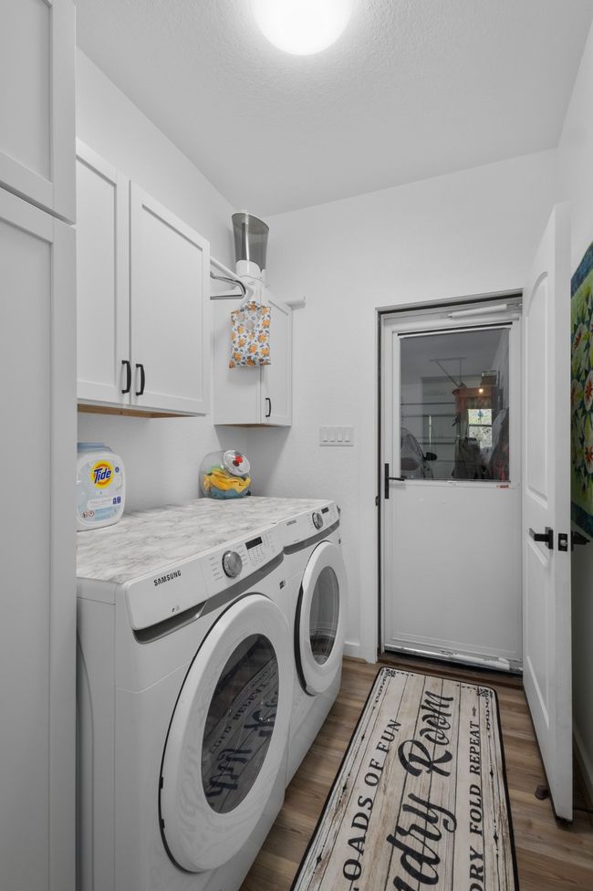 Laundry area featuring cabinet space, washing machine and clothes dryer, and wood finished floors | Image 32