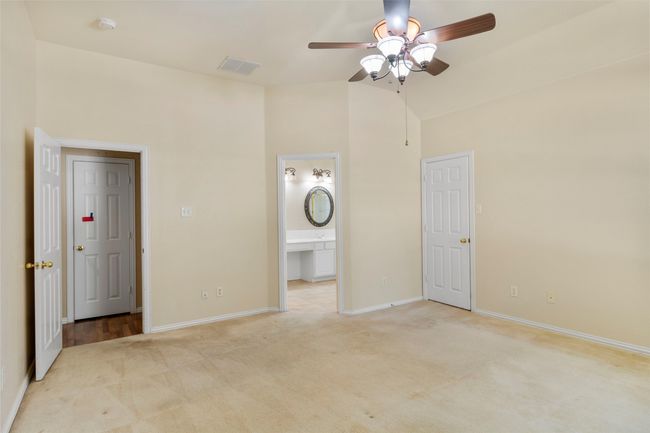 Unfurnished bedroom with light carpet, baseboards, connected bathroom, high vaulted ceiling, and a ceiling fan | Image 12