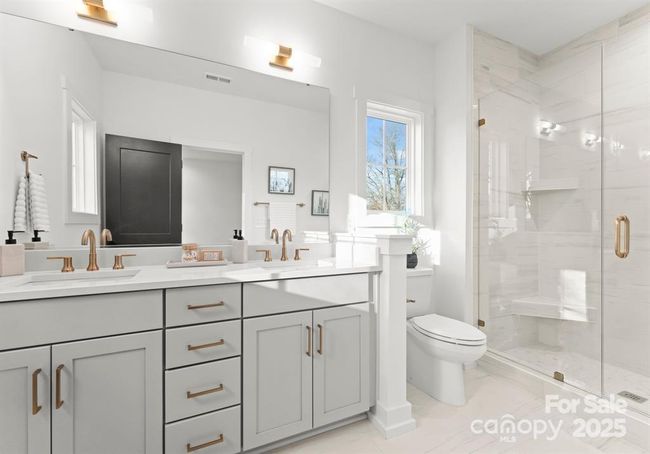 This luxurious primary bathroom showcases a spacious walk in shower with elegant finishes and a sleek double vanity featuring quartz countertops- designed for both comfort and style. | Image 15