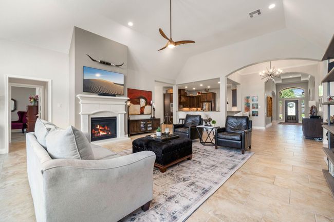 This light and bright spacious living room is the perfect layout for entertaining or just relaxing. Whether it's simply a night in or entertaining family and friends, this home has ample open space for everyone to enjoy! Featuring custom ceiling fan, large tile flooring, large windows with blinds, soaring high ceilings, recessed lighting with wonderful access to your gorgeous kitchen. | Image 5
