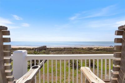 Oceanfront view from your private deck, overlooking a sandy beach, grassy dunes, and a clear sky. | Image 1