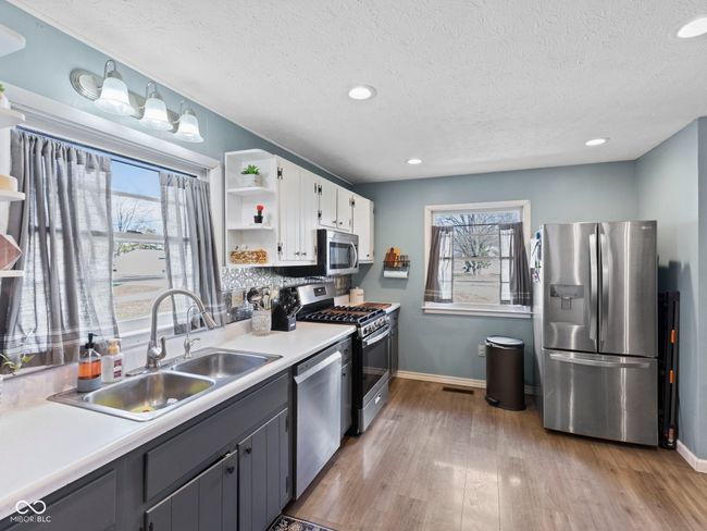 kitchen with white cabinets, plenty of natural light, appliances with stainless steel finishes, a sink, and open shelves | Image 11