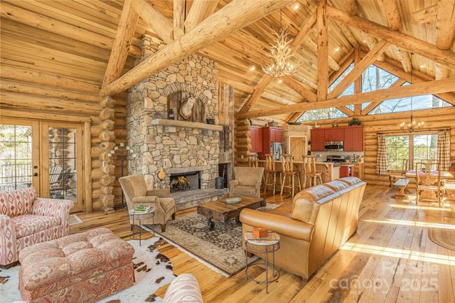 The living area features a sunning wood-burning rock fireplace serving as a rustic yet elegant focal point. The hardwood floors enhance the room's rich, inviting ambiance complementing the natural textures of the stone. Overhead, exposed beams add architectural character creating a welcoming retreat perect for relaxation. | Image 14