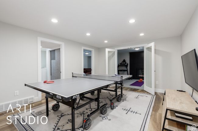 Playroom with a glass covered fireplace, light wood-style floors, visible vents, and recessed lighting | Image 25