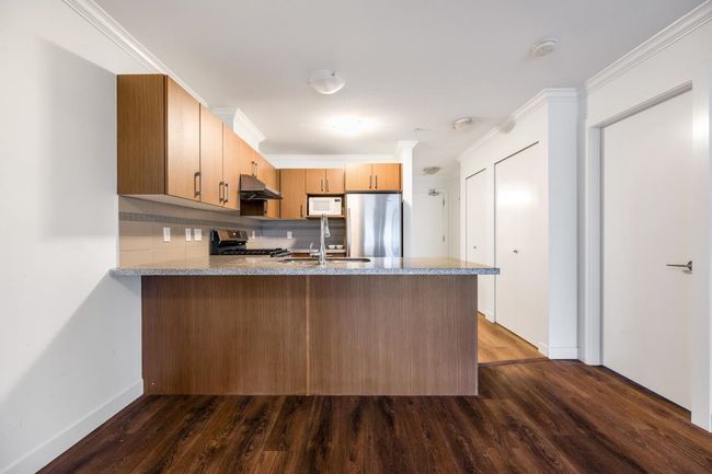 Kitchen featuring white microwave, gas range, a peninsula, freestanding refrigerator, and dark wood-style floors | Image 9