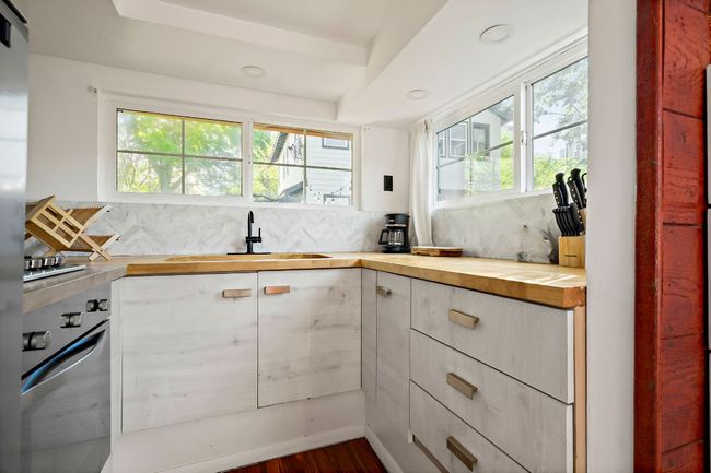 Kitchen featuring decorative backsplash, butcher block counters, a sink, and a healthy amount of sunlight | Image 27