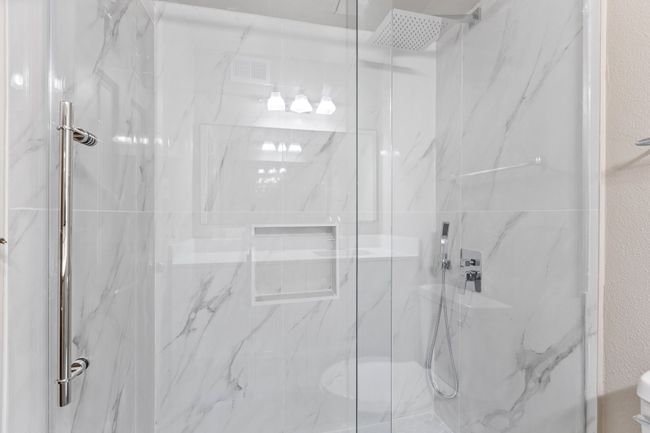 Bathroom with a textured wall, toilet, and a marble finish shower | Image 17