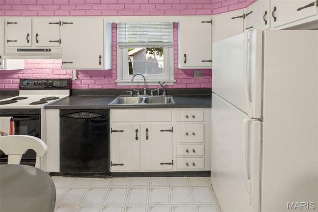 Kitchen with white appliances, dark countertops, light floors, and white cabinets | Image 20