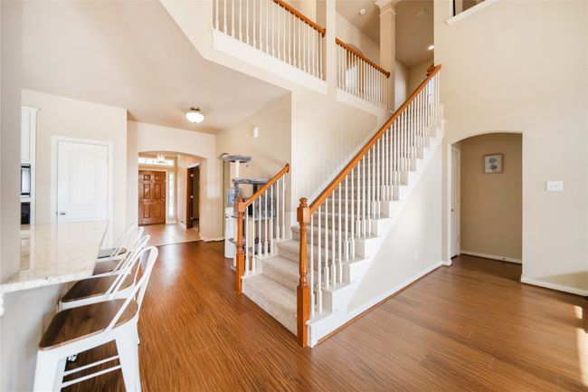 Stairway featuring arched walkways, wood finished floors, a towering ceiling, and decorative columns | Image 19