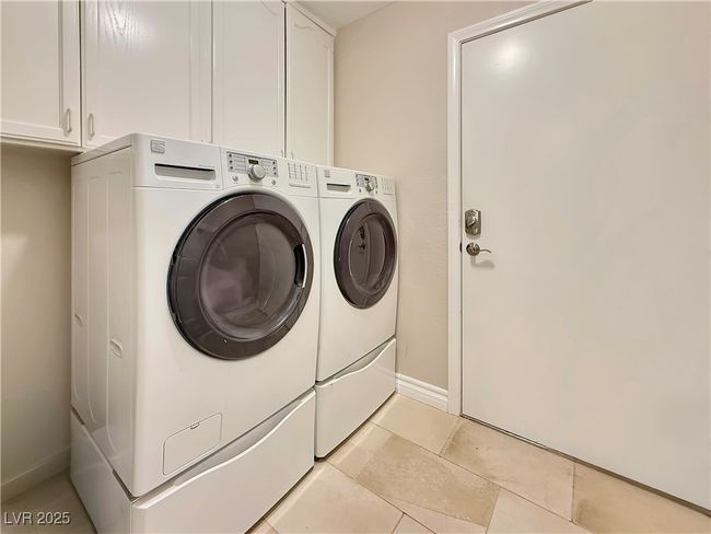 Laundry room with light tile patterned floors, baseboards, cabinet space, and washer and clothes dryer | Image 41
