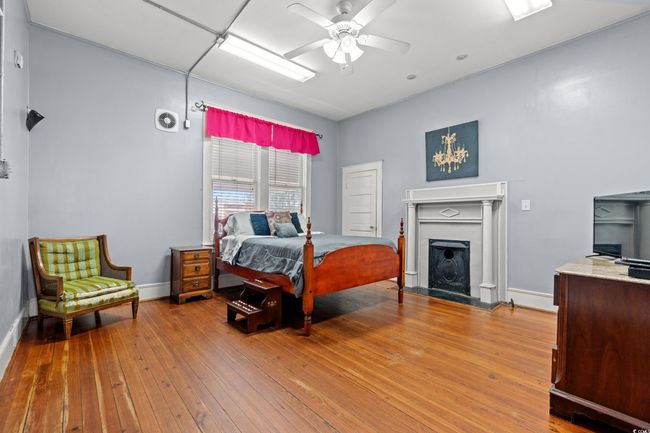 Bedroom featuring hardwood / wood-style floors, a fireplace, and ceiling fan | Image 13