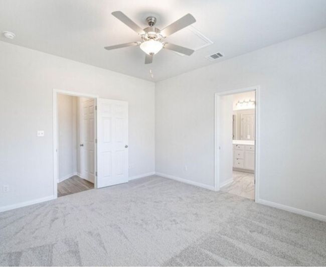 Unfurnished bedroom featuring light carpet, a ceiling fan, and ensuite bathroom | Image 10