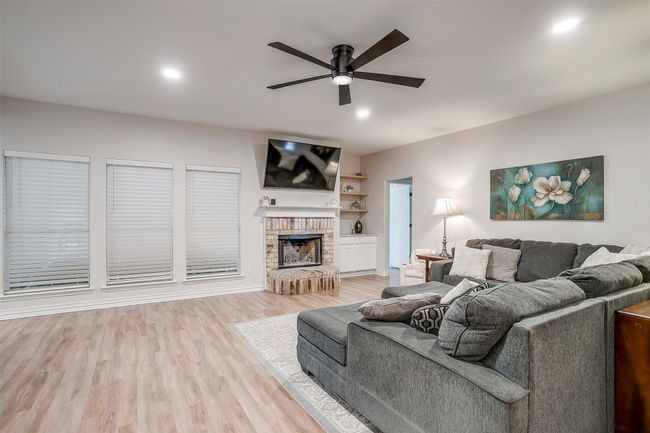 Living room with a ceiling fan, light wood-style floors, recessed lighting, and a brick fireplace | Image 8