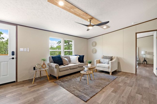 Living room featuring light wood-style floors, a textured ceiling, a ceiling fan, and crown molding | Image 12