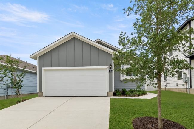 View of front facade featuring driveway, an attached garage, a front lawn, and board and batten siding | Image 15