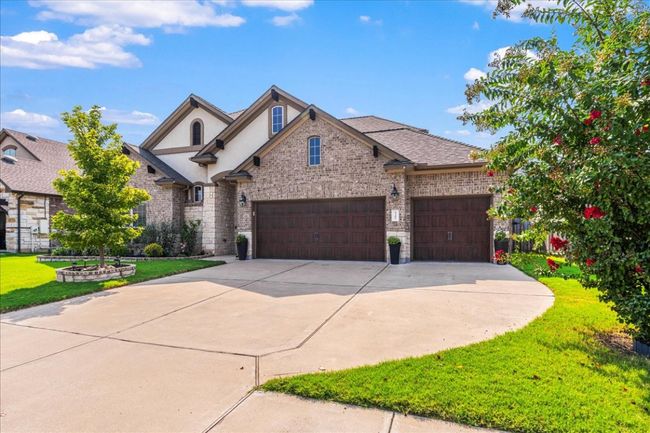 French country style house with a front lawn, a garage, brick siding, and driveway | Image 39