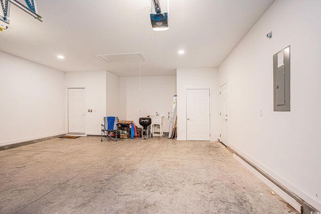 Garage featuring electric panel, a garage door opener, and recessed lighting | Image 25
