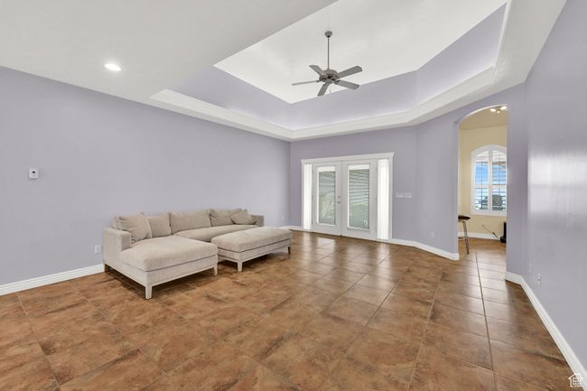Living room featuring tile patterned floors, arched walkways, a ceiling fan, a tray ceiling, and baseboards | Image 15