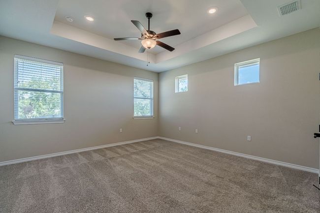 Unfurnished room featuring a raised ceiling, carpet flooring, and ceiling fan | Image 24