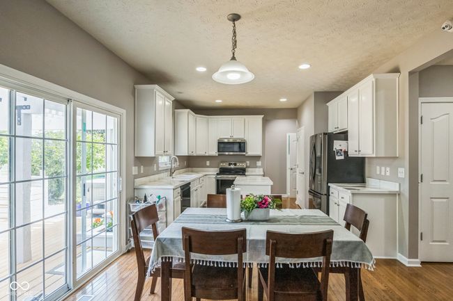 kitchen featuring appliances with stainless steel finishes, light countertops, light wood-type flooring, white cabinets, and a textured ceiling | Image 15
