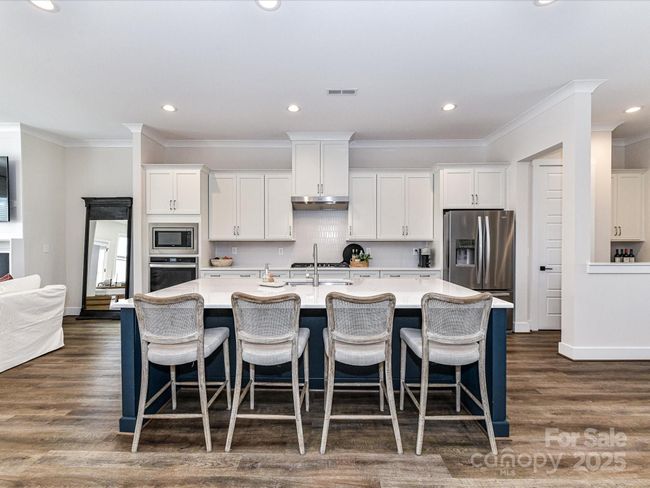 Kitchen offers quartz counters, stainless steel appliances, gas cook top, huge 8' island, custom lighting, plenty of cabinets for storage & pantry! | Image 6