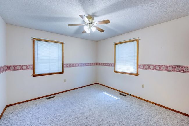 Carpeted empty room with a ceiling fan, a textured ceiling, and baseboards | Image 10