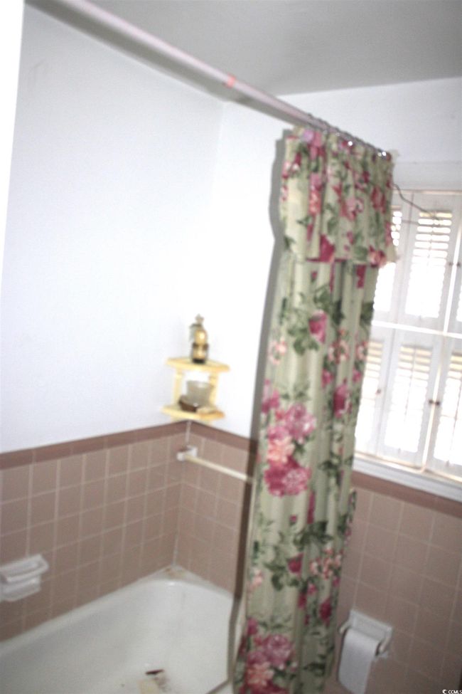 Bathroom with a bath, plenty of natural light, curtained shower, and tile walls | Image 21
