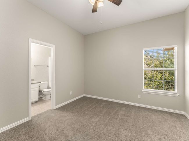 Unfurnished bedroom with ensuite bath, a ceiling fan, baseboards, and light carpet | Image 29