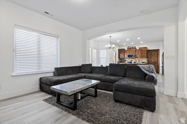 Living room with a wealth of natural light, light hardwood / wood-style floors, and a notable chandelier | Image 6