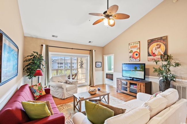 Living room featuring wainscoting, wood finished floors, ceiling fan, and high vaulted ceiling | Image 13