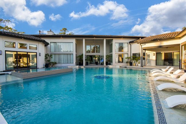This luxurious home features a stunning outdoor pool surrounded by elegant architecture. Large windows and sliding doors provide ample natural light and seamless indoor-outdoor living. Perfect for relaxation and entertaining. | Image 5