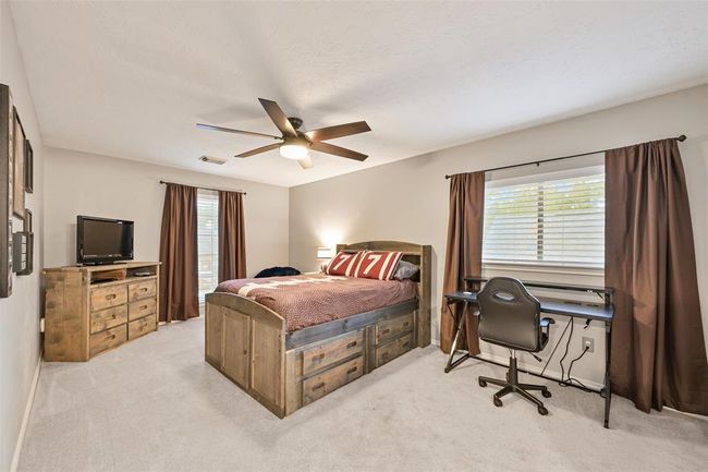 Another generously sized secondary bedroom boasts plush carpeting, neutral walls, and great natural light from dual windows. A ceiling fan, walk-in closet, and en suite bath make it both comfortable and functional. | Image 20