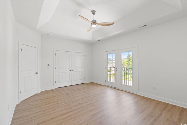Unfurnished bedroom featuring access to exterior, light wood-style floors, french doors, a raised ceiling, and ceiling fan | Image 14
