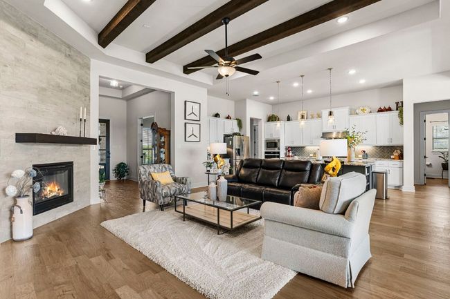 Living area with beamed ceiling, wood finished floors, a tile fireplace, and baseboards | Image 11