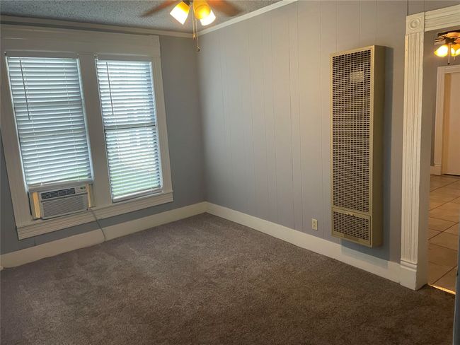 Empty room featuring a ceiling fan, carpet flooring, a heating unit, and crown molding | Image 6