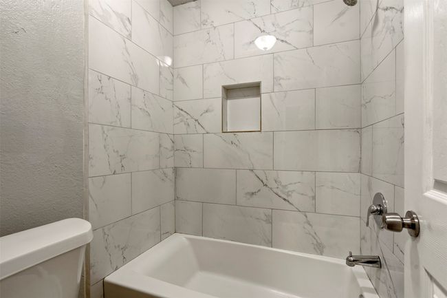 Bathroom featuring shower combination, toilet, and a textured wall | Image 15