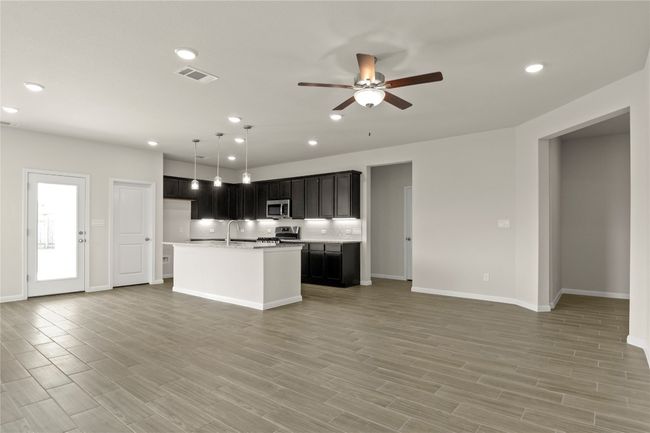 Kitchen with stainless steel appliances, open floor plan, a ceiling fan, light countertops, and a kitchen island with sink | Image 10