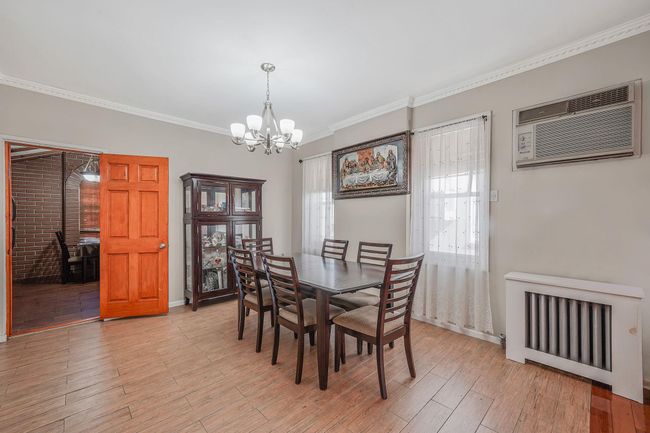 Dining area with an AC wall unit, a chandelier, ornamental molding, and light wood finished floors | Image 10