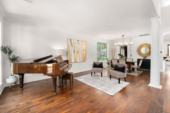 Sitting room featuring a chandelier, dark wood finished floors, crown molding, and decorative columns | Image 5