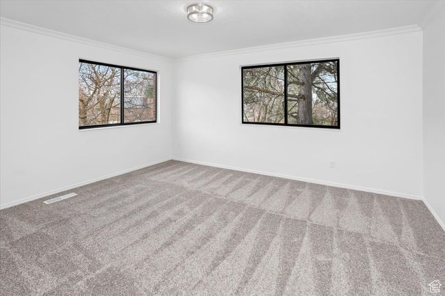 Carpeted empty room with crown molding, baseboards, and visible vents | Image 23