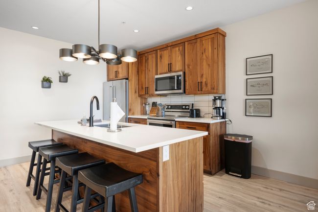 Kitchen with appliances with stainless steel finishes, brown cabinetry, light wood-style floors, and recessed lighting | Image 43