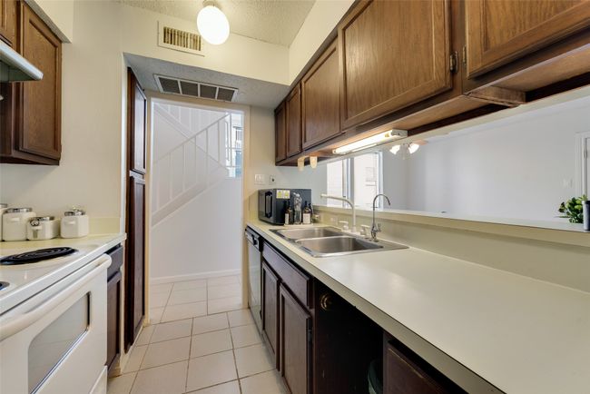 Kitchen with dishwasher, white range with electric cooktop, sink, light tile patterned floors, and extractor fan | Image 7
