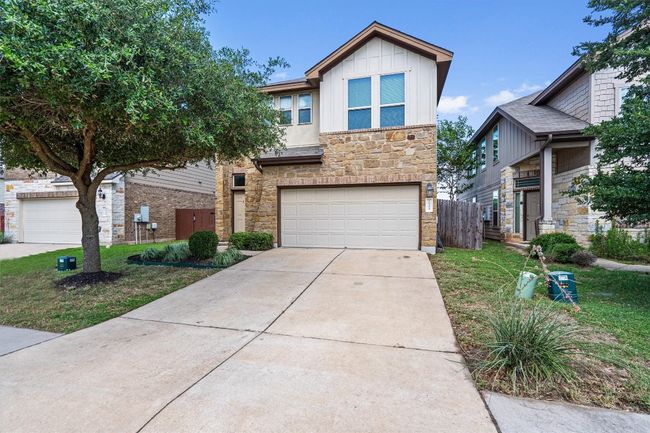 Traditional-style house with stone siding, board and batten siding, a garage, and concrete driveway | Image 39